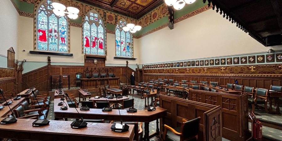 A large courtroom with wooden benches and stained glass windows.