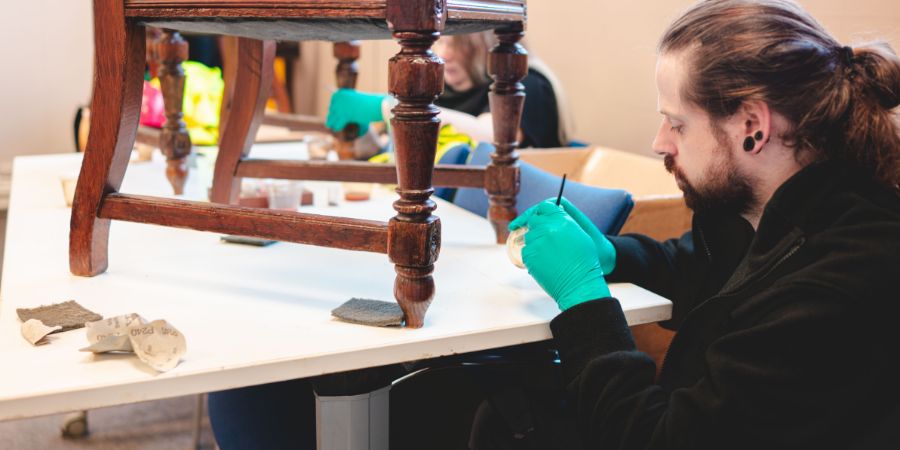 A volunteer restoring an old wooden chair.