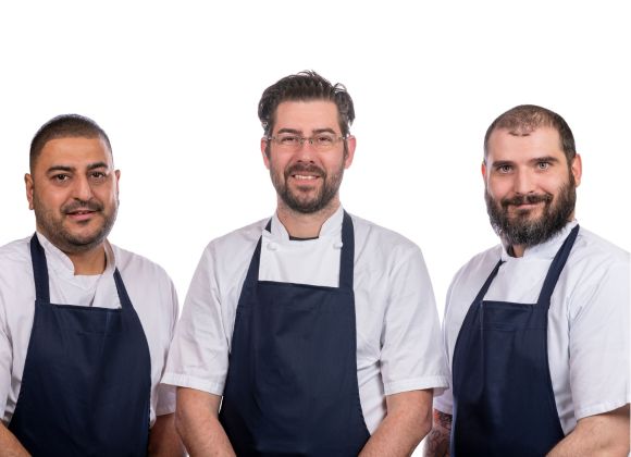 3 chefs wearing blue aprons.