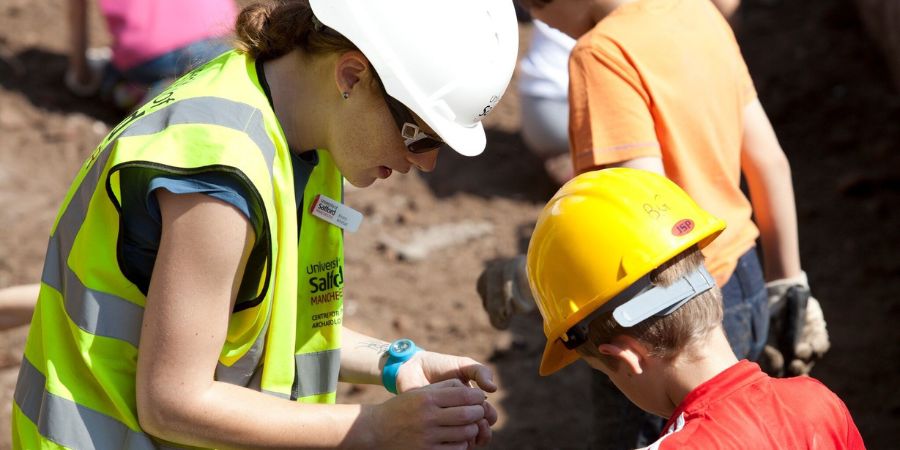 2 young people taking part in an archaeological dig.